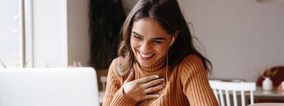 A woman laughing with her therapist during an online therapy session