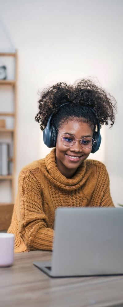 A woman wearing headphones and looking at her laptop for a qualified supervision session in Florida