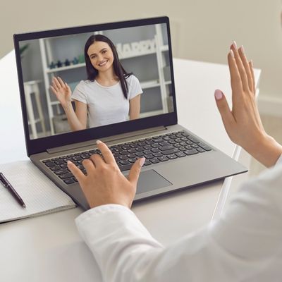 Two women waving at each other during an online therapy session